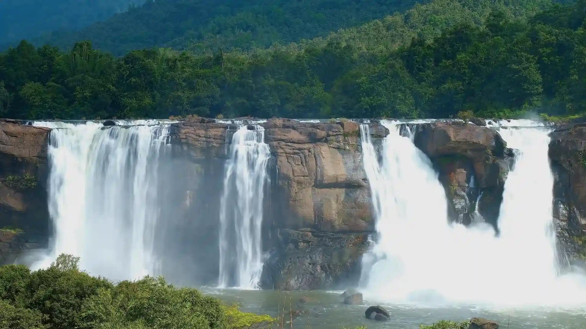 Athirappilly waterfall flowing below forested hills in Kerala